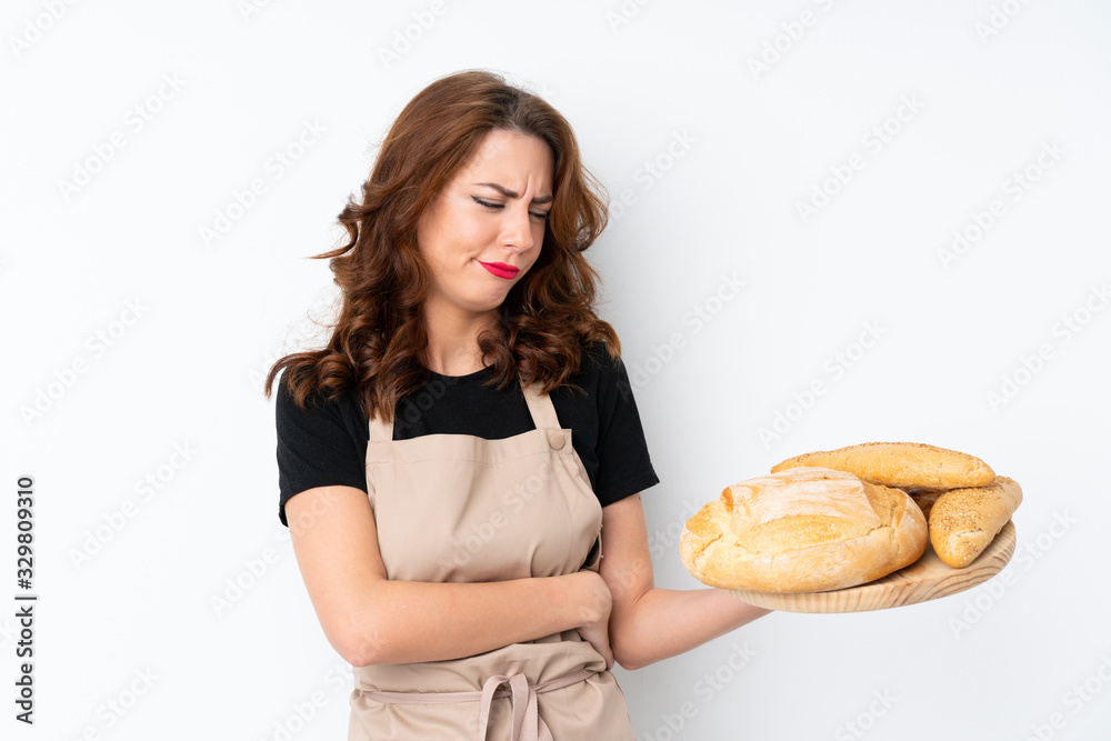 Woman in chef uniform. Female baker holding a table with several breads with sad expression Woman in chef uniform. Female baker holding a table with several breads with sad expression