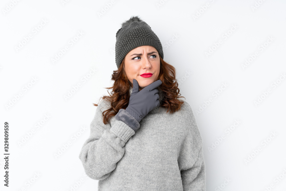 Young Russian woman with winter hat over isolated white background thinking an idea