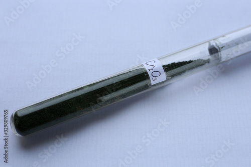 Fotografie Trivalent green chromium oxide in a test tube with the formula, on a white background