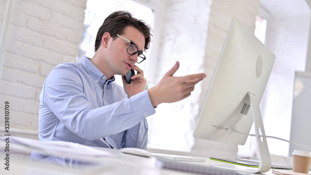 Serious Working Young Man Talking on Smartphone and Discussing Work Serious Working Young Man Talking on Smartphone and Discussing Work