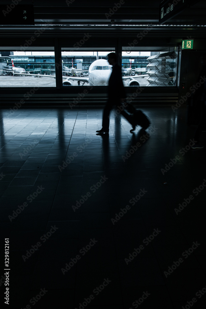 Fototapeta premium Airport rush: people with their suitcases walking along a corridor (motion blurred image; color toned image)