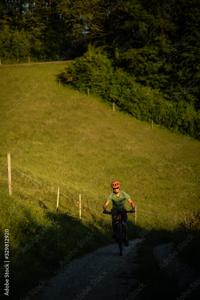 Handsome young man biking on a mountain bike enjoying healthy active lifestyle outdoors in summer (shallow DOF)