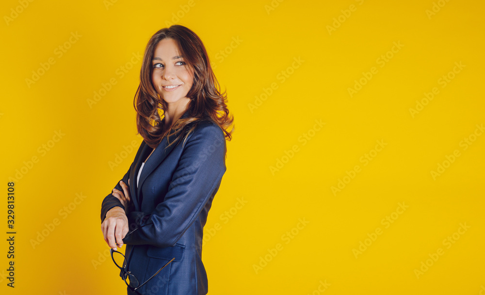 A beautiful young woman dressed elegantly as a teacher, like a bissnes lady, smiling and well placed on a yellow background A beautiful young woman dressed elegantly as a teacher, like a bissnes lady, smiling and well placed on a yellow background