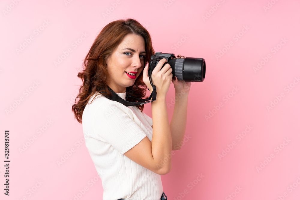 Young Russian woman over isolated pink background with a professional camera Young Russian woman over isolated pink background with a professional camera