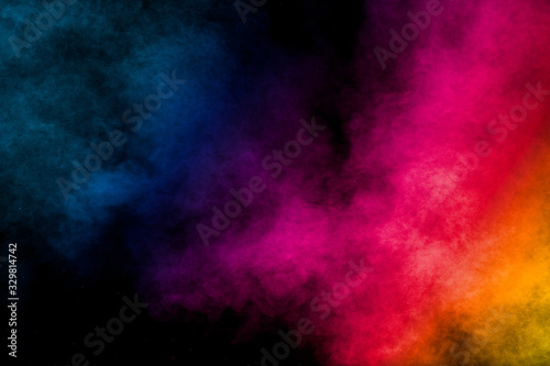 Multi colored particles explosion on black background.Colorful dust splash on dark background. © Pattadis
