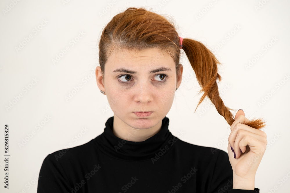 Obraz premium Closeup portrait of a sad redhead teenage girl with childish hairstyle looking offended isolated on white backround.