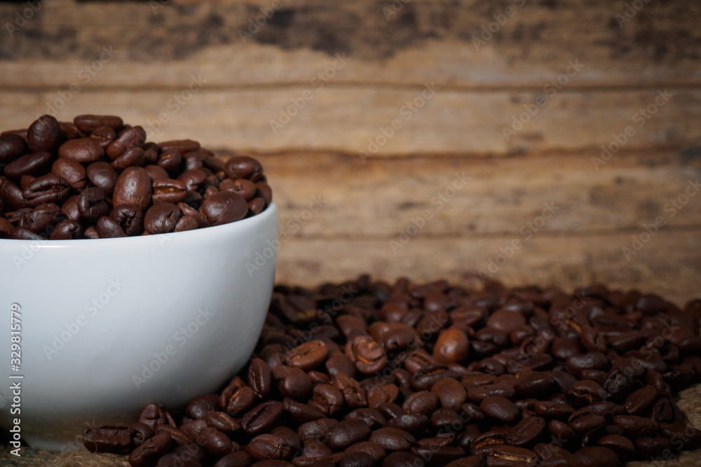 Fototapeta premium Coffee beans in a cup on a wooden table