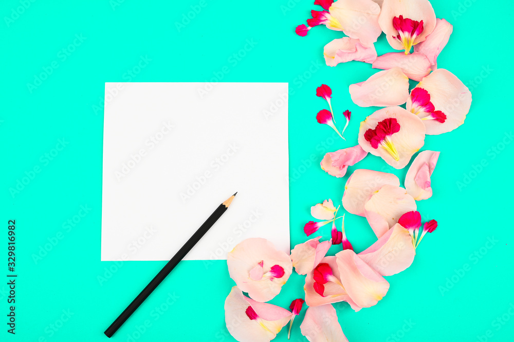 Flat lay blogger or freelancer workspace with a paper card, light pink petals on a color background Flat lay blogger or freelancer workspace with a paper card, light pink petals on a color background