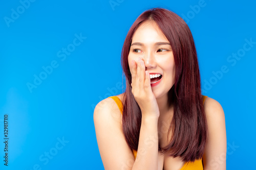 Cute young asian woman, lovely sense of humor with laughing Happy young lady standing isolated over blue background Portrait of gesturing good looking Asia woman laughing while looking aside. cheerful
