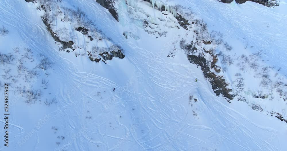 Person skiing downhill and stopping on a mountain slope in the Swiss Alps. Captured by drone.