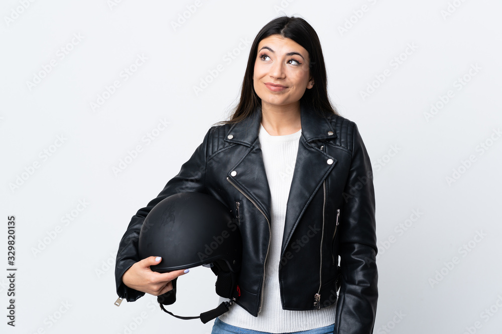 Young woman holding a motorcycle helmet over isolated white background standing and looking to the side