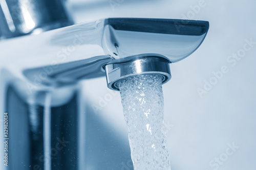 Obraz na płótnie Flowing water from tap on blue background
