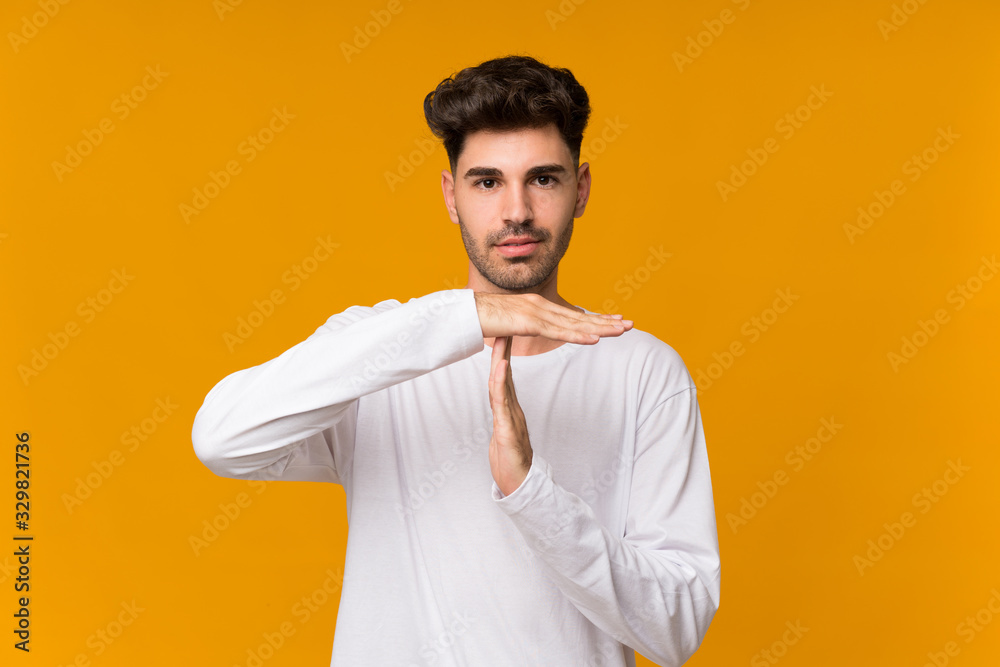 Young man over isolated orange background making time out gesture Young man over isolated orange background making time out gesture