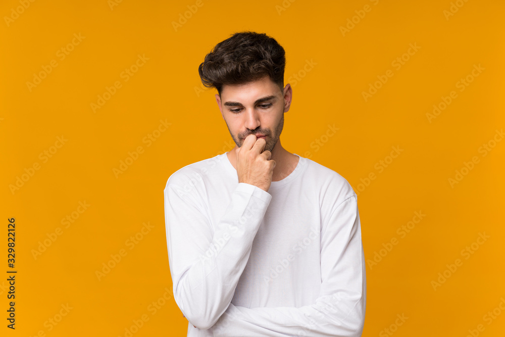 Young man over isolated orange background having doubts Young man over isolated orange background having doubts