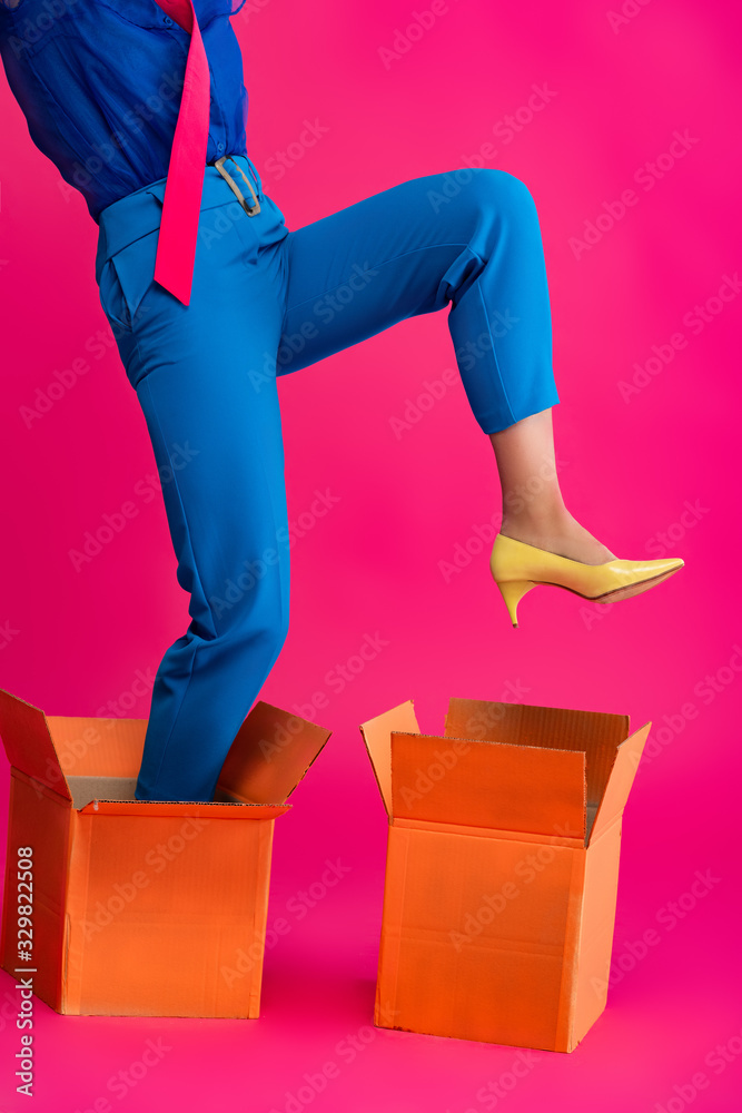 Fototapeta cropped view of fashionable girl standing in cardboard boxes on pink