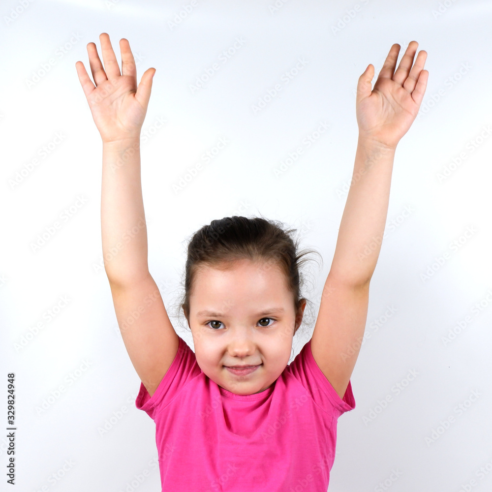 Caucasian little smiling girl raising her hands up on white background. Sport, physical training, physical jerks, healthy lifestyle, health, physical exercise concept. Caucasian little smiling girl raising her hands up on white background. Sport, physical training, physical jerks, healthy lifestyle, health, physical exercise concept.
