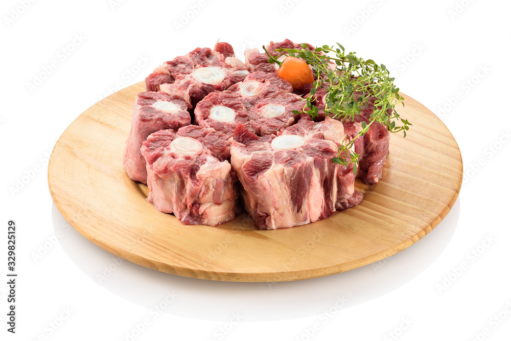 Raw oxtail, the culinary name for the tail of cattle, ready to be cooked. On a cutting board, isolated on white background.