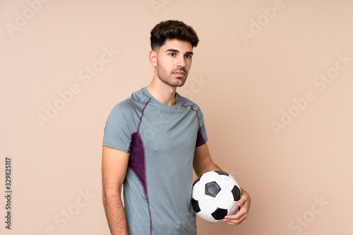 Young man over isolated background with soccer ball