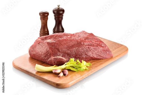 Raw silverside beef or outside flat, ready to be cooked. On a cutting board with some garlic aside, isolated on white background photo