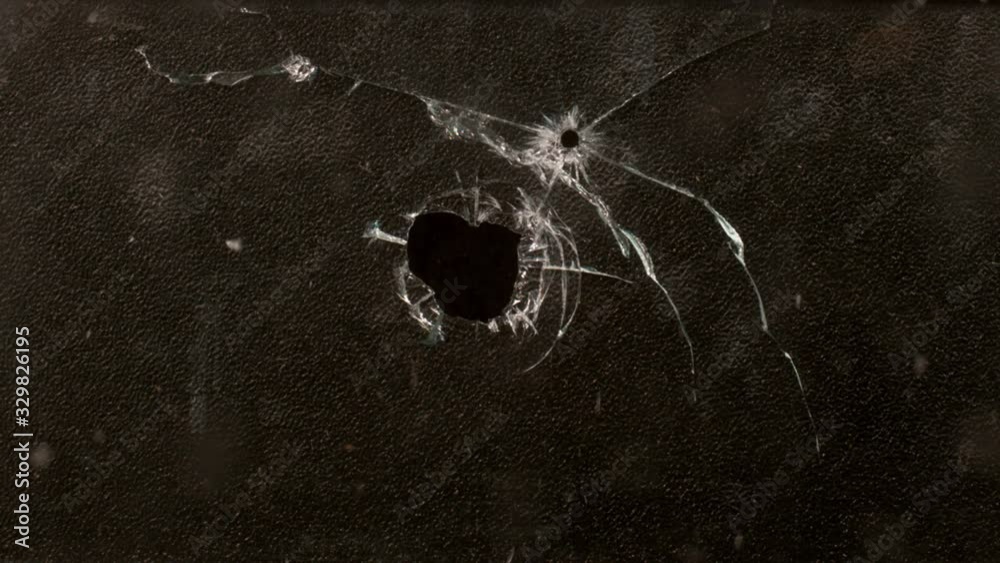 Shot Glass breaking with bullet holes on black background