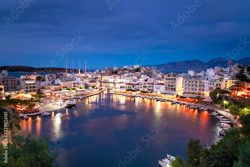 Beautiful sunset at Agios Nikolaos city, Port at Aegean sea. Crete,Greece. Peaceful harbor of Voulismeni Lake. Long promenade with restaurants. Panoramic view of seaport with yachts and boats at quay