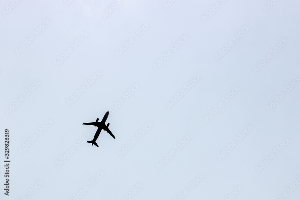 Black silhouette of a flying airplane against a blue gray sky background Black silhouette of a flying airplane against a blue gray sky background