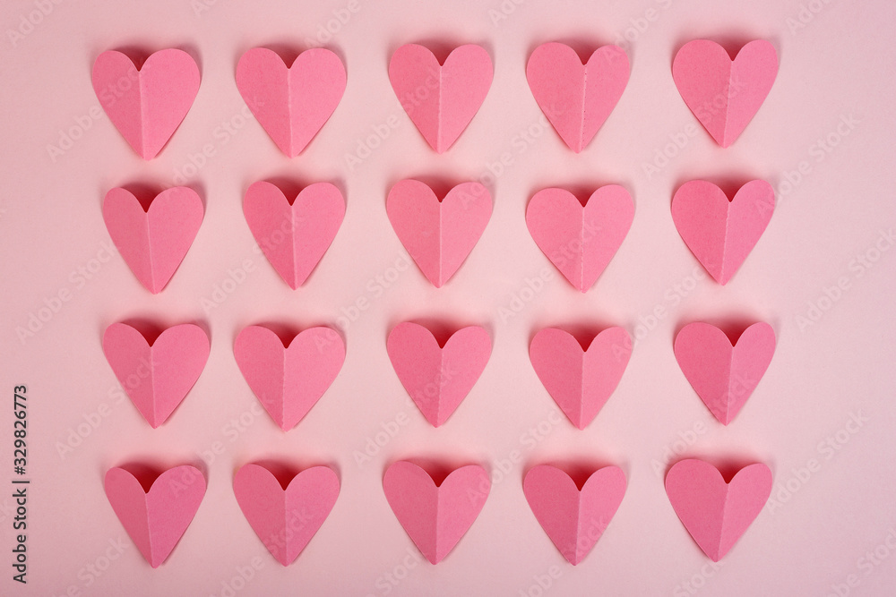 Fototapeta Top view of pink paper hearts on pink background. Abstract paper hearts cut out arranged in rows