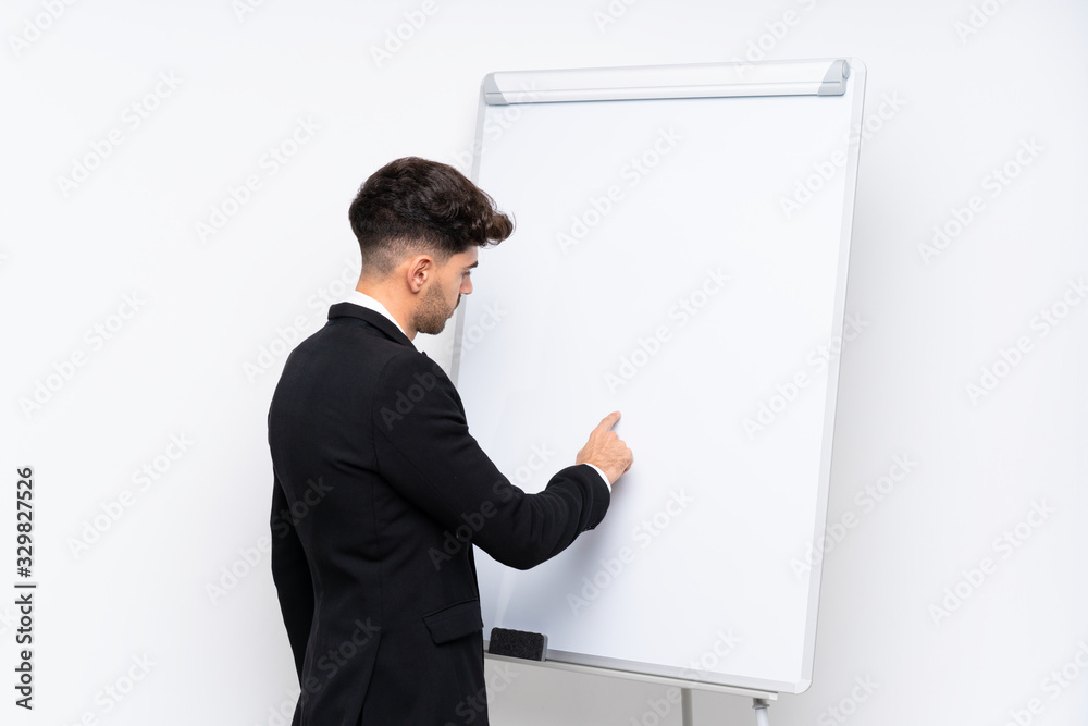 Young businessman giving a presentation on white board giving a presentation on white board and writing in it Young businessman giving a presentation on white board giving a presentation on white board and writing in it