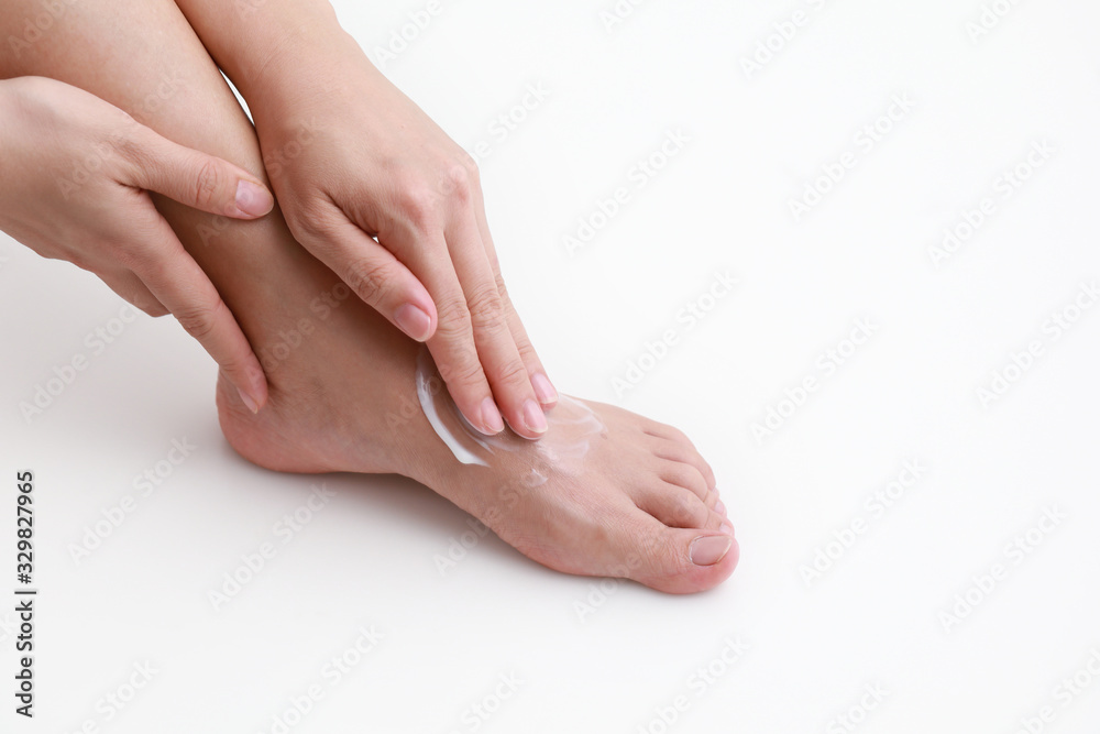 Woman applying moisturiser cream on her leg over white background Woman applying moisturiser cream on her leg over white background
