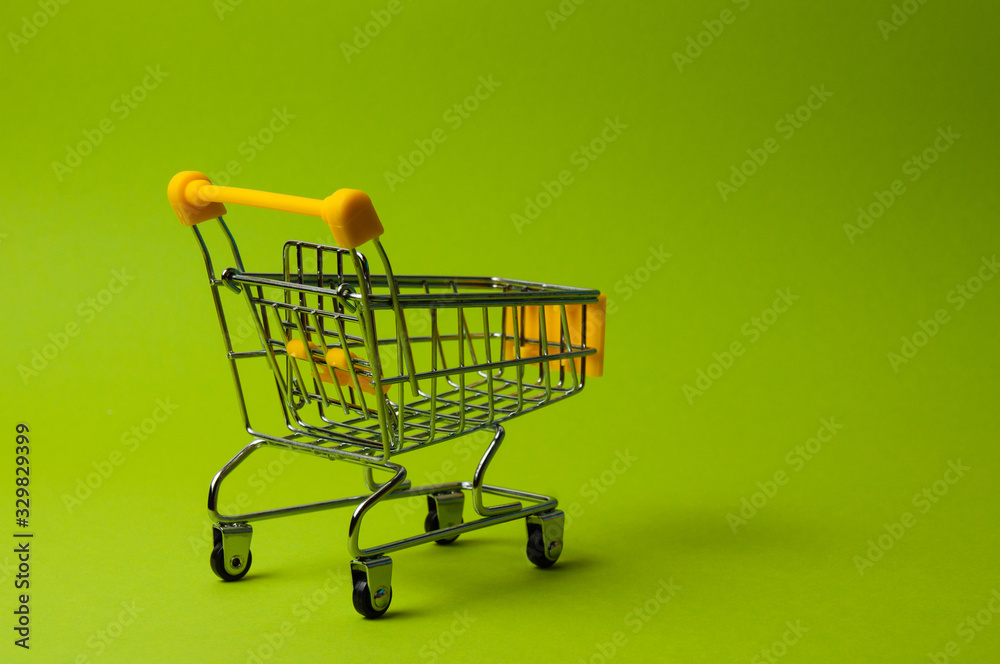 Trolley for shopping on a green background. Supermarket food price concept, holiday discounts Trolley for shopping on a green background. Supermarket food price concept, holiday discounts