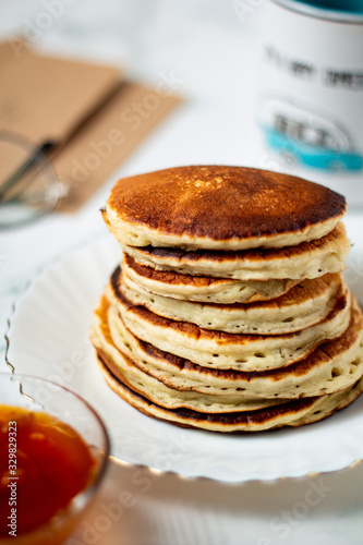 Tasty breakfast with hot american pancakes with apricot jam on the white table. Mug and envelope background