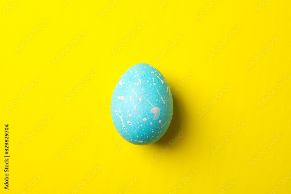 Blue Easter egg on yellow background, close up