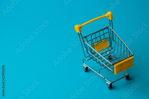 Trolley for shopping on a blue background. Supermarket food price concept, holiday discounts
