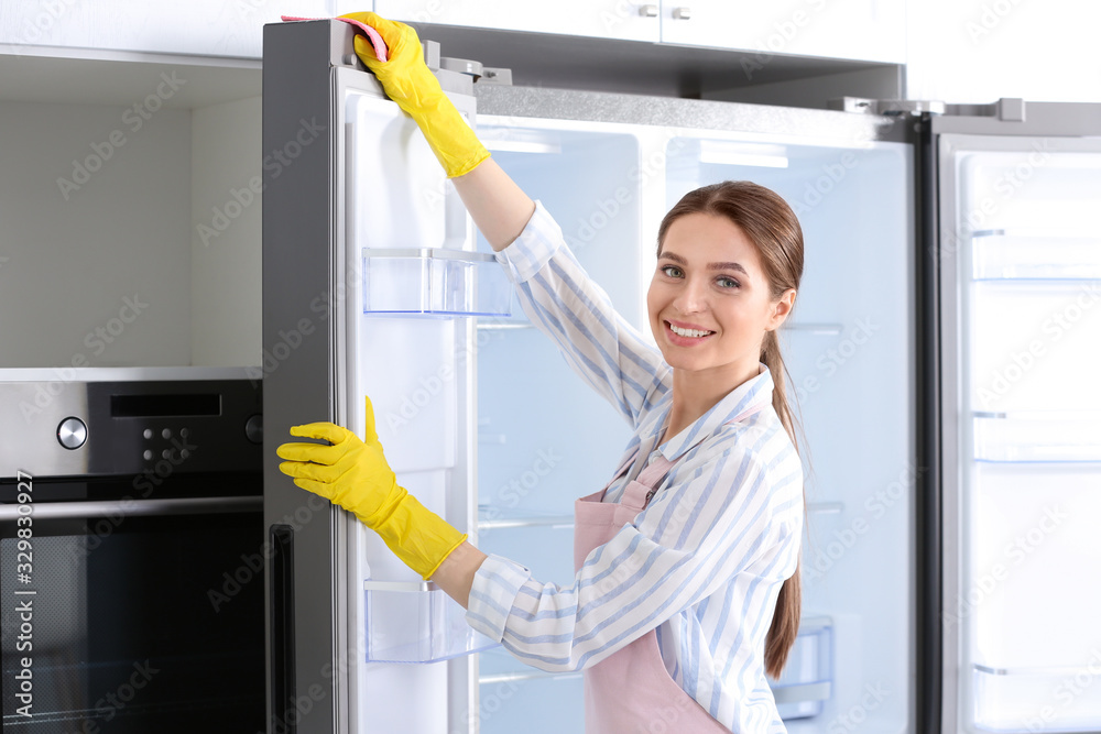 Woman in rubber gloves cleaning refrigerator at home Woman in rubber gloves cleaning refrigerator at home