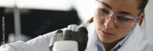 Fotografie Portrait of concentrated serious woman putting material under microscope