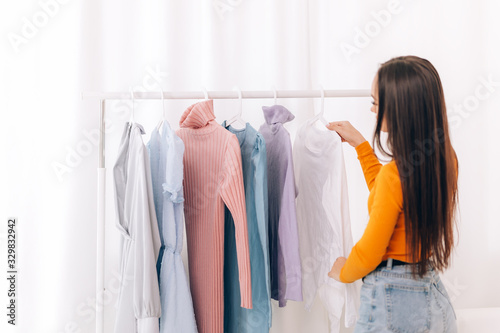 A young girl chooses what clothes to wear, girl looks at clothes in white room