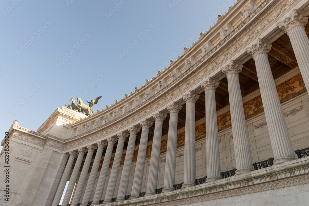 Detail of the colonnade of the altar of the Fatherland, Vittoriano, Rome, Italy. Upper cornice with carved statues of the Italian regions. Quadriga with winged victory of the homeland.