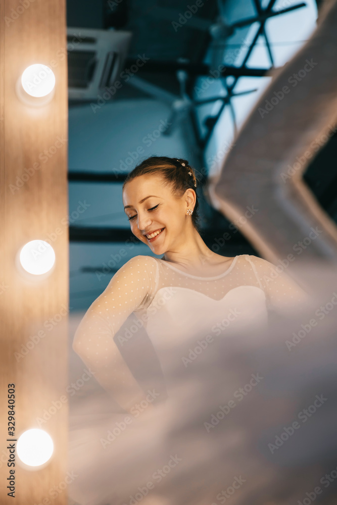 Elegant ballerina in white dress dancing in studio