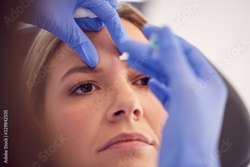 Woman Sitting In Chair Being Give Anti Ageing Injection Between Eyes By Female Doctor