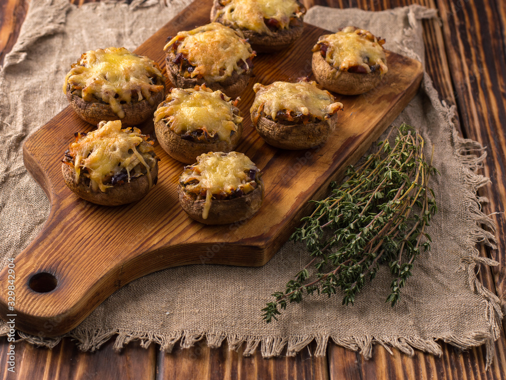 baked mushrooms with vegetables and cheese on a wooden board. baked mushrooms with vegetables and cheese on a wooden board.