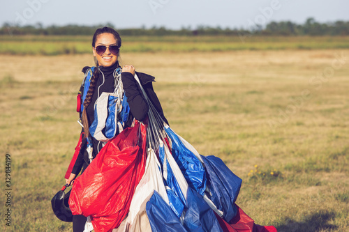 Beautiful pretty woman skydiver holding a parachute canopy after landing.