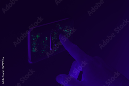 Ultraviolet UV blacklight exposing germs and virus on hand touching dirty light switch