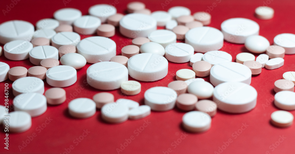 Heap of white pills, tablets, capsules on red background. Drug prescription for treatment medication health care concept wth copy space. Heap of white pills, tablets, capsules on red background. Drug prescription for treatment medication health care concept wth copy space.