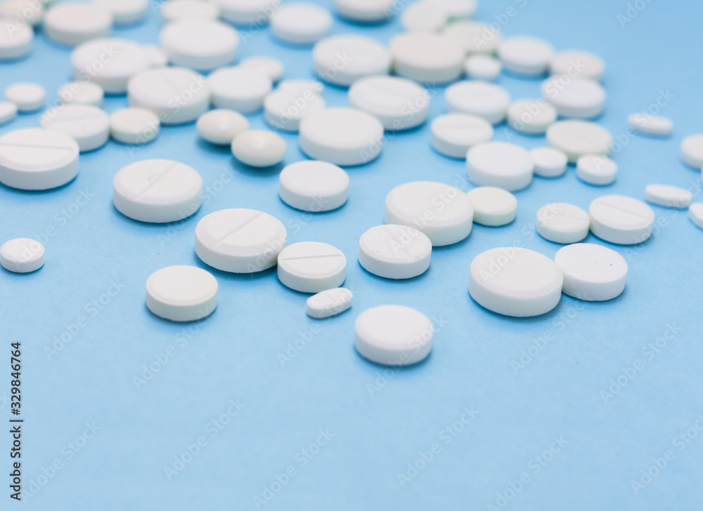 Heap of white pills, tablets, capsules on blue background. Drug prescription for treatment medication health care concept wth copy space. Heap of white pills, tablets, capsules on blue background. Drug prescription for treatment medication health care concept wth copy space.