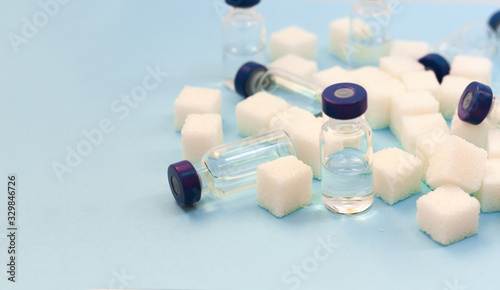 Fotografie Sugar addiction, insulin resistance, unhealthy diet, sugar cubes and bottles of insulin on blue background, diabetes protection medical concept