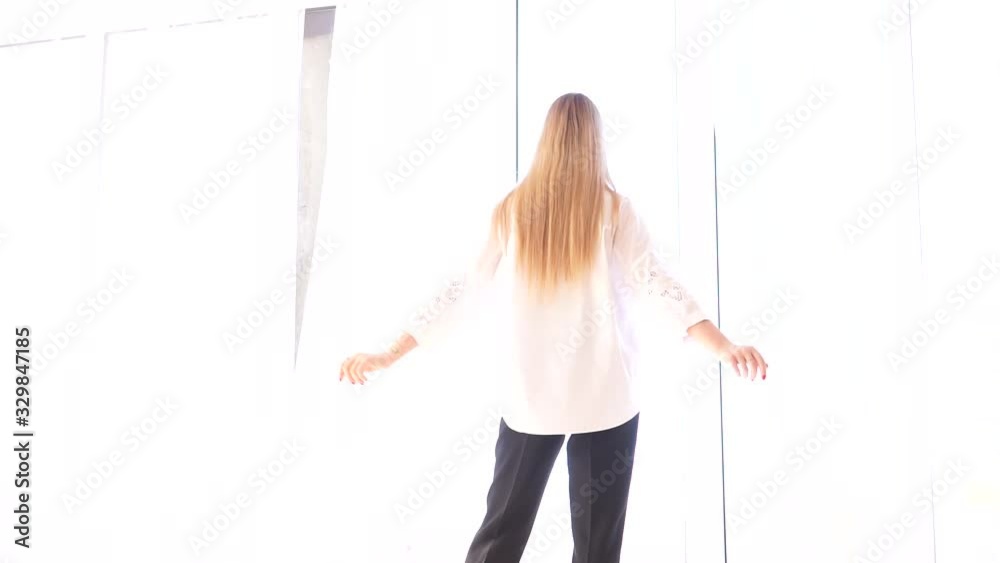 Portrait of a young white-haired girl by the window. Pretty young girl in a white shirt near the window. In the video, the girl poses against a large window. Light room. Portrait of a young white-haired girl by the window. Pretty young girl in a white shirt near the window. In the video, the girl poses against a large window. Light room.