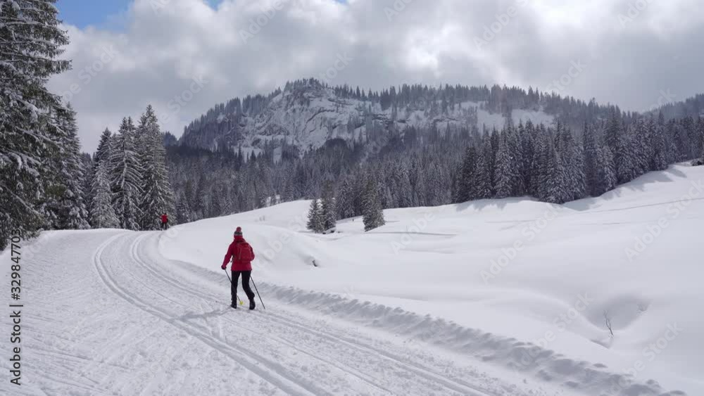 nice senior woman , crosscountry skiing in fresh fallen snow on a ski track in the Allgau Alps, Bavaria, Germany nice senior woman , crosscountry skiing in fresh fallen snow on a ski track in the Allgau Alps, Bavaria, Germany