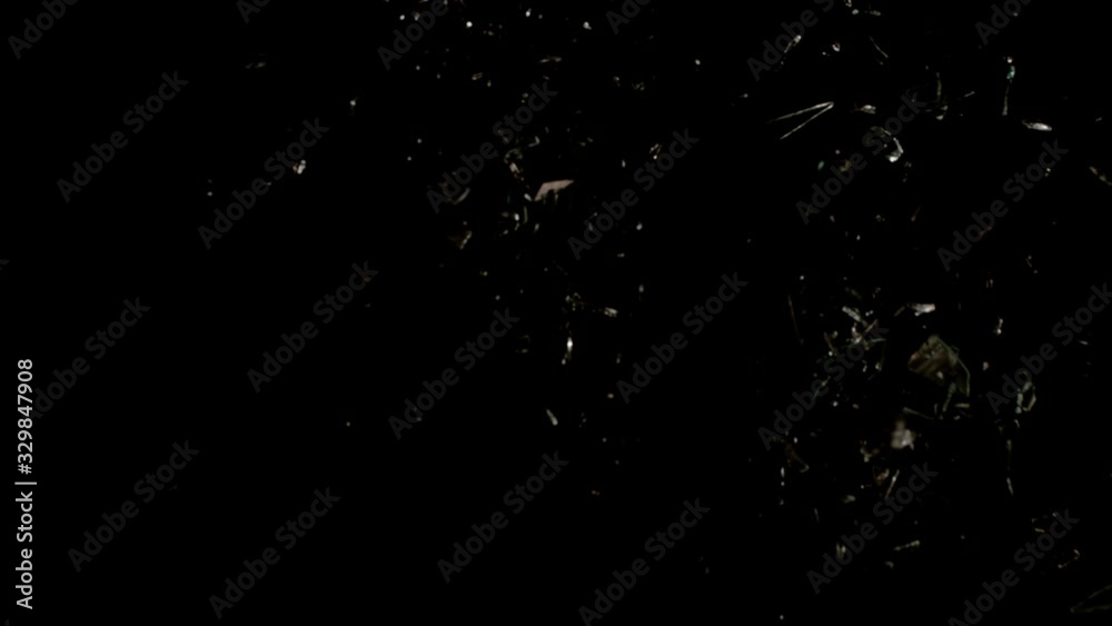 Glass breaking in slow motion on black background