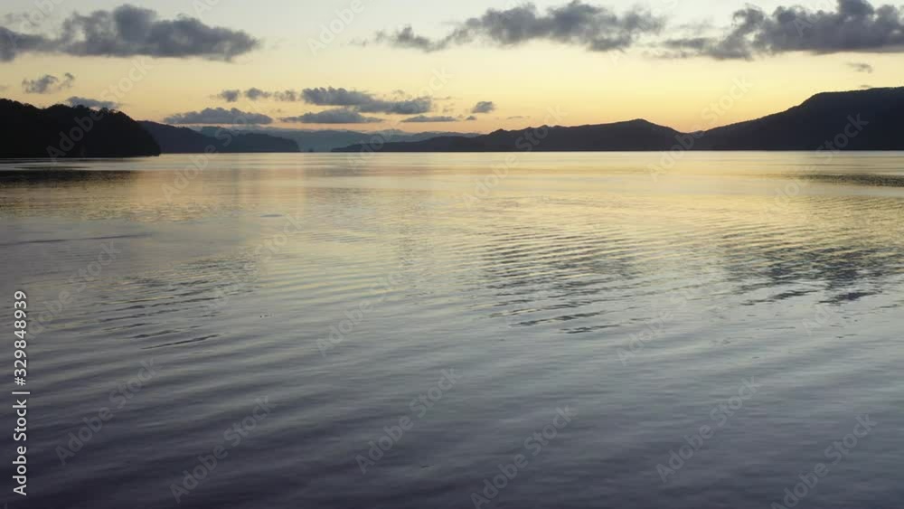A tranquil dawn illuminates the calm waters of Alyui Bay in Raja Ampat, Indonesia. This remote, equatorial area is known for its extraordinary marine biodiversity. A tranquil dawn illuminates the calm waters of Alyui Bay in Raja Ampat, Indonesia. This remote, equatorial area is known for its extraordinary marine biodiversity.