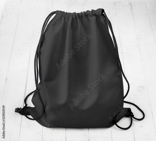 black backpack with strings on planked surface